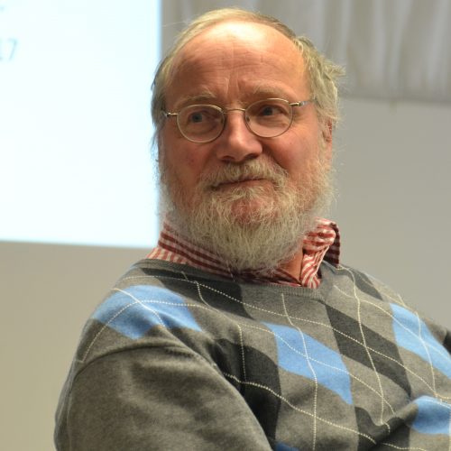 Ein älterer Herr mit Halbglatze und grauem Bart und