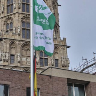 Eine grün-weiße Flagge weht vor einem gotischen Turm.