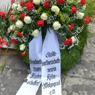 Ein Grabkranz mit weißen Rosen und roten Nelken.