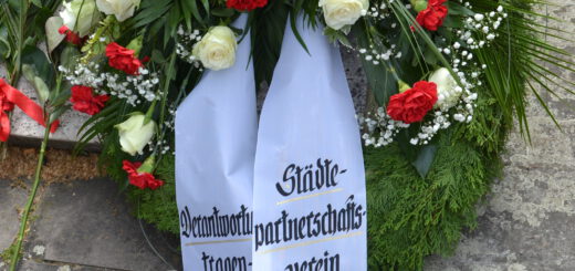 Ein Grabkranz mit weißen Rosen und roten Nelken.