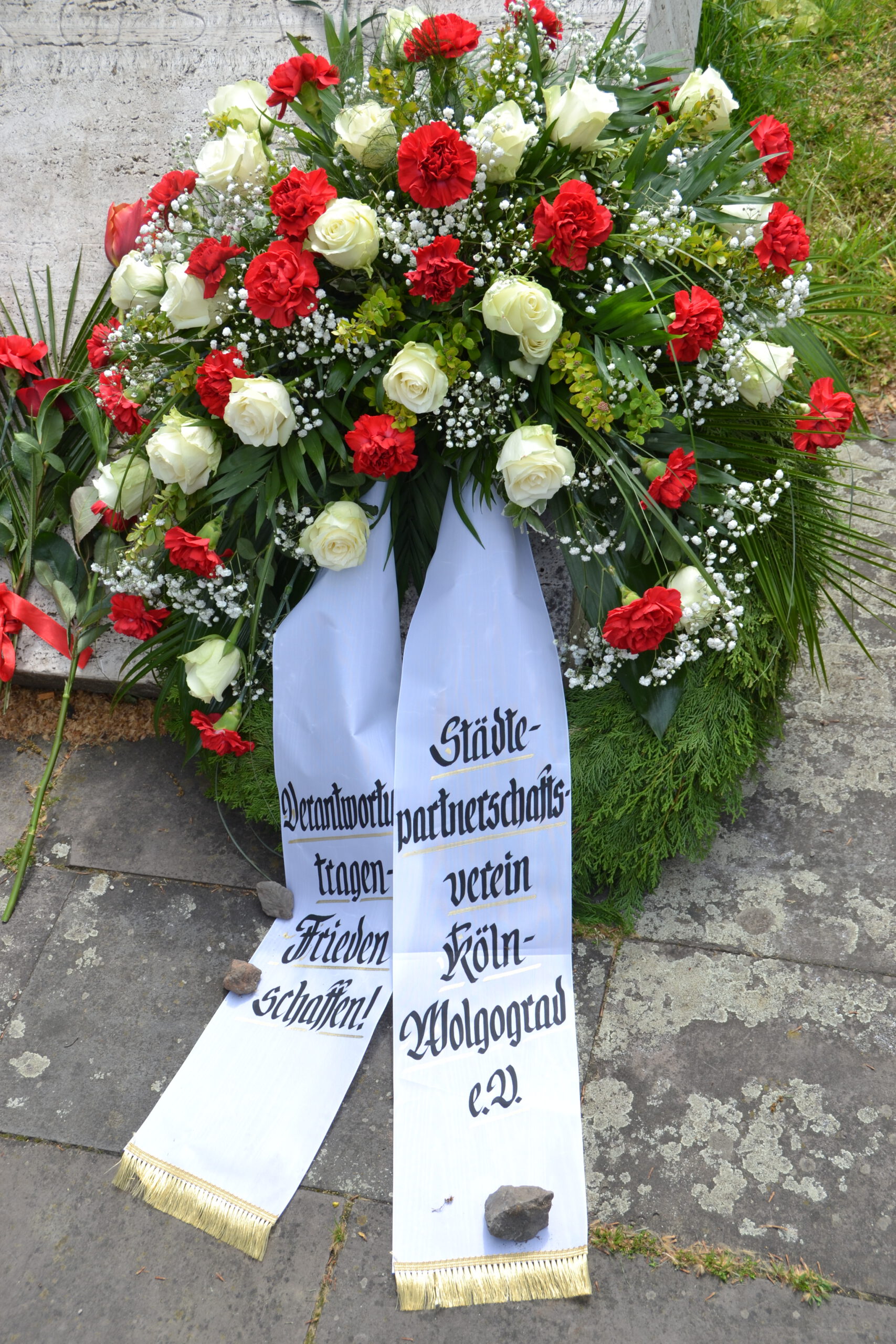 Ein Grabkranz mit weißen Rosen und roten Nelken.