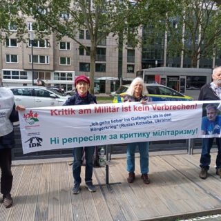 Vier Personen halten ein Transparent.