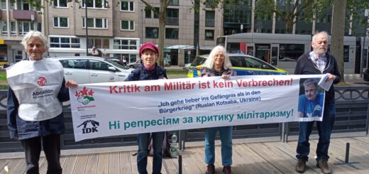 Vier Personen halten ein Transparent.