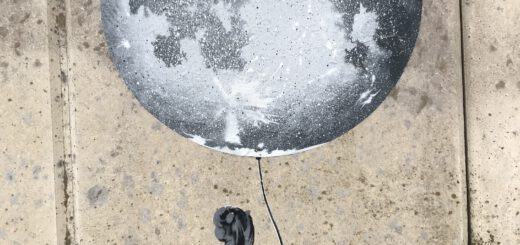 Ein kleines Mädchin in rotem Sommerkleid schaut verträumt vom Betrachter weg, während es eine große grau-weiße Weltkugel wie einen Luftballon an einem Faden hält. Bild auf dem Fuß einer Betonwand angebracht.