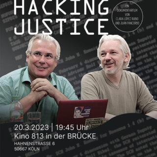 zwei Männer mit weißen Haaren sitzen nebeneinander vor einem aufgeklappten Laptop und schauen entspannt und freundlich nach vorn links. Auf dem Laptop-Deckel ein ein Aufkleber mit "Stand with Snowden" zu sehen.