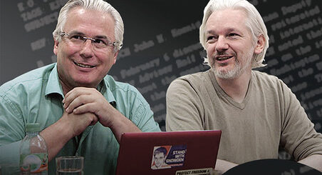 zwei Männer mit weißen Haaren sitzen nebeneinander vor einem aufgeklappten Laptop und schauen entspannt und freundlich nach vorn links. Auf dem Laptop-Deckel ein ein Aufkleber mit "Stand with Snowden" zu sehen.