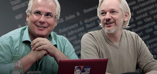 zwei Männer mit weißen Haaren sitzen nebeneinander vor einem aufgeklappten Laptop und schauen entspannt und freundlich nach vorn links. Auf dem Laptop-Deckel ein ein Aufkleber mit "Stand with Snowden" zu sehen.