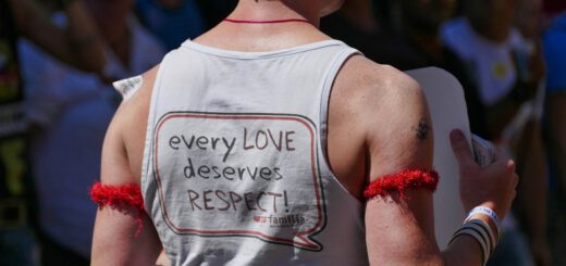 Ein Mann steht mit dem Rücken zum Betrachter; er trägt ein weißes Top mit Aufschrift.