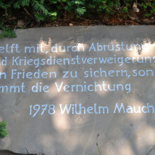 Ein heller Sandstein mit weißer Inschrift.