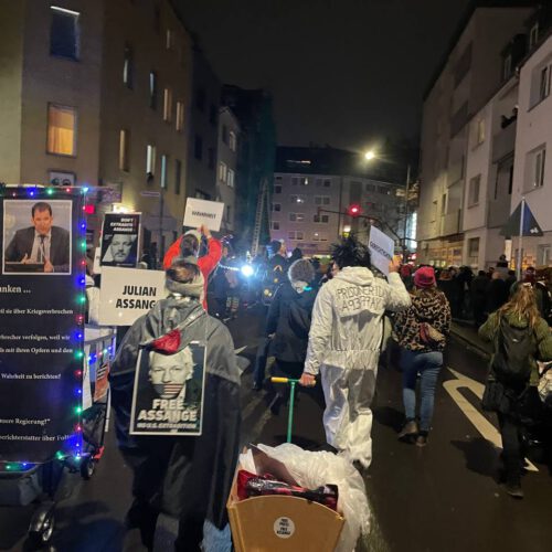 Ein nächtlicher Demozug zwischen mehrstöckigen Wohnhäusern mit vielen "Julian-Assange"-Schildern.