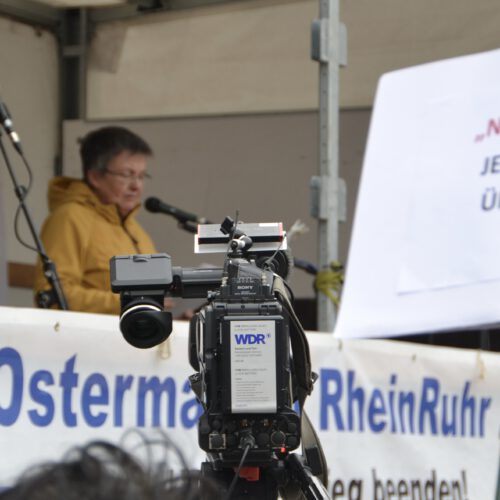 Eine WDR-Fernsehkamera ist auf eine Bühne mit Rednerin gerichtet.