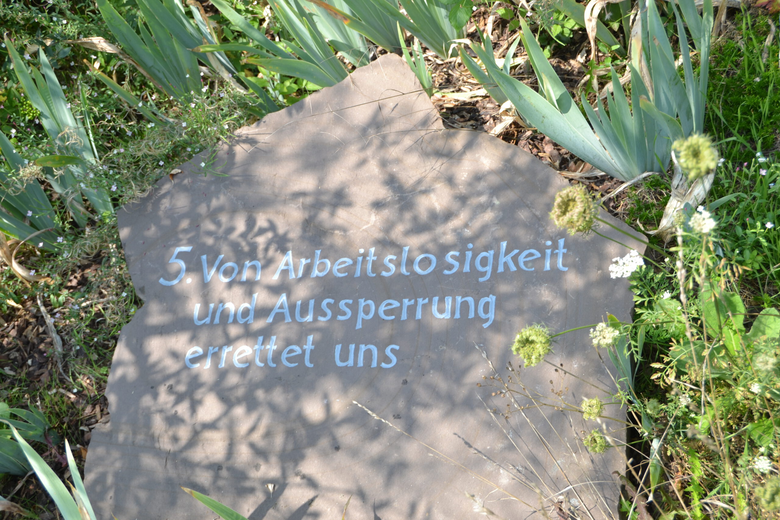 Ein heller Sandstein mit weißer Inschrift.