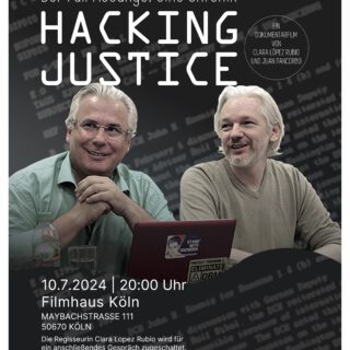 zwei Männer mit weißen Haaren sitzen nebeneinander vor einem aufgeklappten Laptop und schauen entspannt und freundlich nach vorn links. Auf dem Laptop-Deckel ein ein Aufkleber mit "Stand with Snowden" zu sehen.