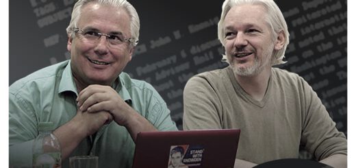 zwei Männer mit weißen Haaren sitzen nebeneinander vor einem aufgeklappten Laptop und schauen entspannt und freundlich nach vorn links. Auf dem Laptop-Deckel ein ein Aufkleber mit "Stand with Snowden" zu sehen.