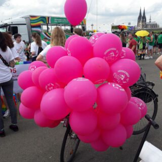 Eine große Menge pinker Luftballons verdeckt das Fahrrad, auf dem sie befestigt ist.